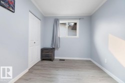 Spacious room featuring light blue walls, wood-finish flooring, and white trim - 