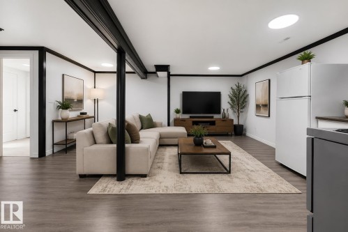 Open-concept living area featuring wood-finish flooring, recessed lighting, and white walls with contrasting black trim - 27 Apache Crescent, Leduc, AB 