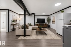 Open-concept living area featuring wood-finish flooring, recessed lighting, and white walls with contrasting black trim - 