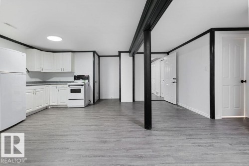 Open-concept living space featuring wood-finish flooring and a full kitchen - 27 Apache Crescent, Leduc, AB 