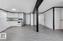 Open-concept living space featuring wood-finish flooring and a full kitchen - 