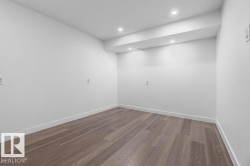 Recessed lighting illuminates an open space featuring light wood-finish flooring and white baseboards - 