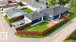 Corner property featuring a dark blue facade, pitched asphalt shingle roof, and a private wooden fence - 