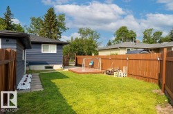 Expansive backyard featuring a manicured lawn, a raised wooden deck, and a full perimeter wood fence - 