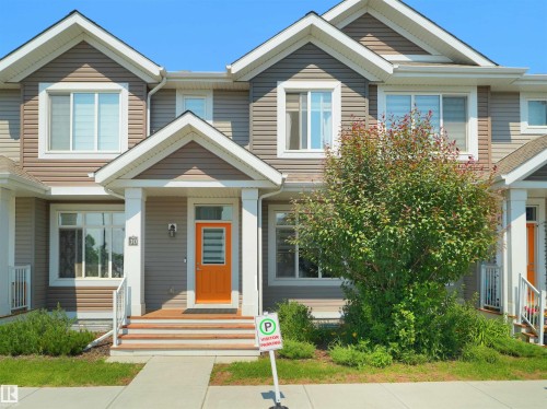 Contemporary townhome exterior featuring multi-toned siding, white trim, and an inviting orange front door with frosted glass - #30 4137 76 St Nw, Edmonton, AB 
