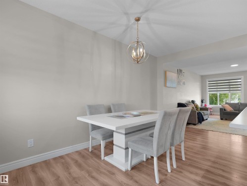 Open-concept dining area featuring wood-finish flooring, a contemporary chandelier, and recessed lighting - #30 4137 76 St Nw, Edmonton, AB 