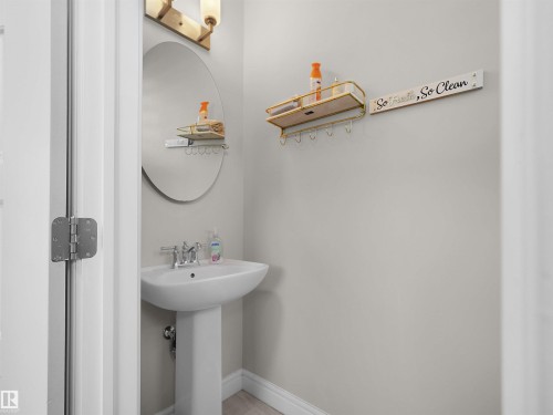 Pedestal sink with chrome fixtures and an oval wall mirror - #30 4137 76 St Nw, Edmonton, AB 