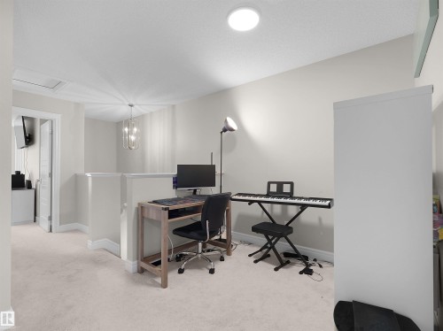 Carpeted loft area featuring a partial wall, overhead lighting, and a contemporary chandelier - #30 4137 76 St Nw, Edmonton, AB 