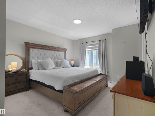 Carpeted room featuring a window with roller shade and drapes, and a ceiling-mounted light fixture - #30 4137 76 St Nw, Edmonton, AB 