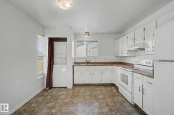 Kitchen featuring white cabinetry, white appliances, a tile backsplash, and wood-finish countertops - 