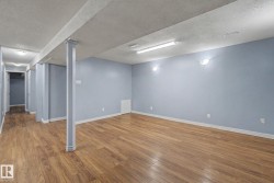Spacious room featuring wood-finish flooring, light blue painted walls, and overhead fluorescent lighting - 