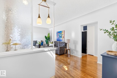 Interior space featuring rich wood-finish flooring, white walls, and a partial wall with textured glass paneling - 16152 110B Avenue Nw, Edmonton, AB - Indoor Photo Showing Other Room