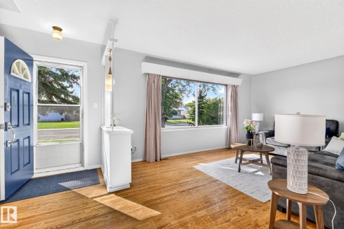 Light-filled living area featuring wood-finish flooring, a large picture window, and neutral wall tones - 16152 110B Avenue Nw, Edmonton, AB - Indoor Photo Showing Living Room
