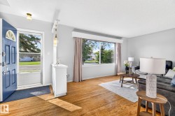 Light-filled living area featuring wood-finish flooring, a large picture window, and neutral wall tones - 