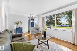 Living area featuring expansive front window, hardwood-finish flooring, white wall tones, and recessed entry nook with built-in shelving - 