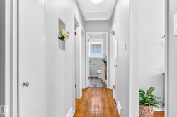 Hallway featuring wood-finish flooring, light gray walls, and white trim - 