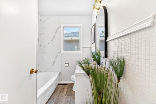 Bathroom featuring a vanity with a white countertop, an arched black-framed mirror, and a three-light fixture - 16152 110B Avenue Nw, Edmonton, AB - Indoor