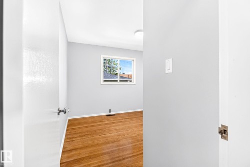 Spacious room featuring wood-finish flooring, a contemporary ceiling light fixture, and a window with white trim - 16152 110B Avenue Nw, Edmonton, AB - Indoor Photo Showing Other Room