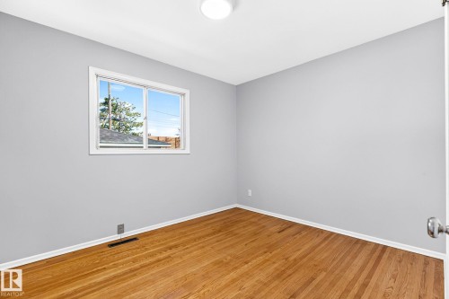 Room featuring wood-finish flooring, light grey painted walls, white baseboards, and a white-framed window - 16152 110B Avenue Nw, Edmonton, AB - Indoor Photo Showing Other Room