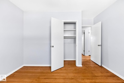 Interior room featuring wood-finish flooring, light gray walls, white trim, and a built-in closet with shelving - 16152 110B Avenue Nw, Edmonton, AB - Indoor Photo Showing Other Room