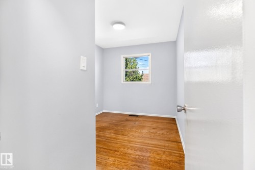 Bright room featuring wood-finish flooring, light blue walls, and a white trim window - 16152 110B Avenue Nw, Edmonton, AB - Indoor Photo Showing Other Room