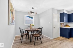 Dining area featuring wood-finish flooring and a contemporary circular chandelier - 