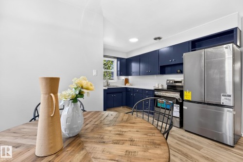 Kitchen featuring deep blue cabinetry, white countertops, a subway tile backsplash, and stainless steel appliances - 16152 110B Avenue Nw, Edmonton, AB - Indoor Photo Showing Other Room