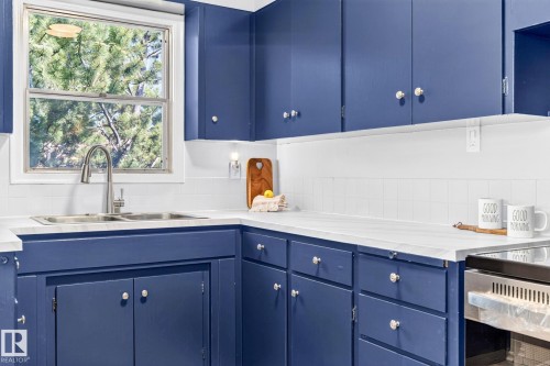 Kitchen featuring blue cabinetry, white countertops, a double basin stainless steel sink with a pull-down faucet, and white subway tile backsplash - 16152 110B Avenue Nw, Edmonton, AB - Indoor Photo Showing Kitchen With Double Sink