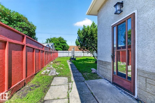 Side entry door with a glass panel, flanked by exterior wall sconce lighting - 16152 110B Avenue Nw, Edmonton, AB - Outdoor