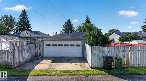 Detached garage featuring a white overhead door with rectangular windows, composition shingle roof, and concrete driveway - 16152 110B Avenue Nw, Edmonton, AB - Outdoor