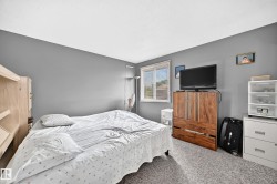 Spacious room featuring neutral gray walls, light textured carpeting, and a window with horizontal blinds - 