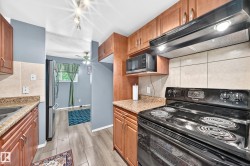 Kitchen featuring wood-finish cabinetry, speckled countertops, and a tile backsplash - 