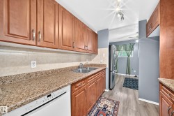 Kitchen featuring wood cabinetry, light-toned stone-finish countertops, and a stainless steel double basin sink - 