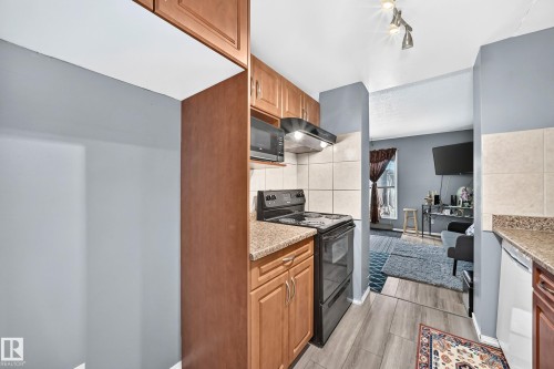 Compact kitchen featuring wood-finish cabinetry, granite-style countertops, an electric range, and a built-in microwave - 243 Abbotsfield Road Nw, Edmonton, AB - Indoor Photo Showing Kitchen