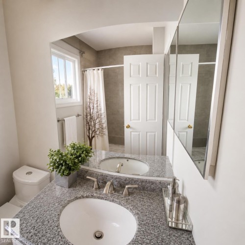 Bathroom featuring a dual vanity with undermount sinks, granite countertop, and brushed nickel fixtures - 1022 106 Street Nw, Edmonton, AB - Indoor Photo Showing Bathroom