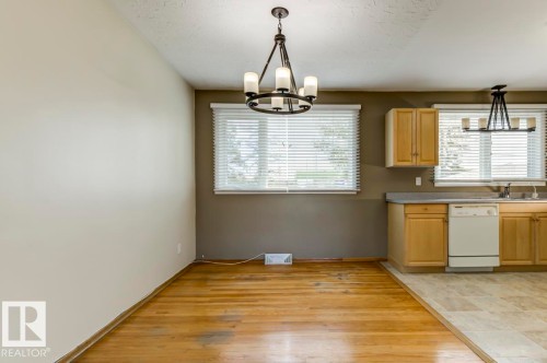 Dining area featuring wood-finish flooring, two large windows with blinds, and an overhead chandelier - 8511 64 Avenue, Edmonton, AB - Indoor Photo Showing Kitchen