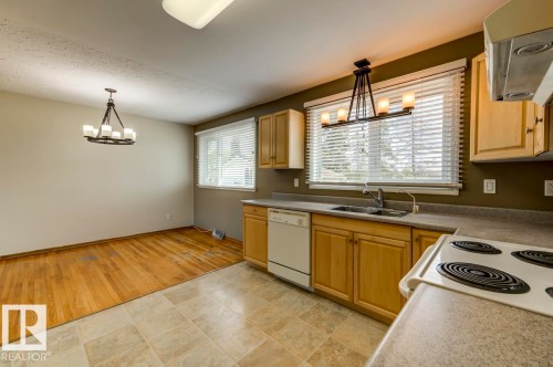 Kitchen and dining area featuring light wood cabinetry, a double basin sink, and a range with a built-in oven - 8511 64 Avenue, Edmonton, AB - Indoor Photo Showing Kitchen With Double Sink