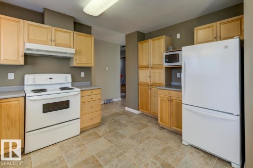 Kitchen featuring wood-finish cabinetry, light-toned countertops, and tile flooring - 8511 64 Avenue, Edmonton, AB - Indoor Photo Showing Kitchen