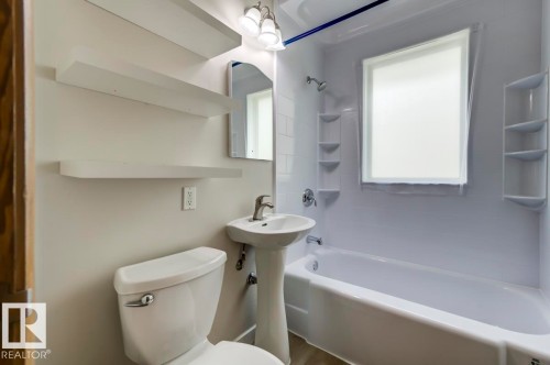 Bathroom featuring a white bathtub, white pedestal sink, and white toilet - 8511 64 Avenue, Edmonton, AB - Indoor Photo Showing Bathroom