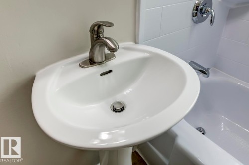 White pedestal sink with a brushed nickel single-handle faucet - 8511 64 Avenue, Edmonton, AB - Indoor Photo Showing Bathroom