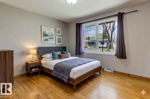 Hardwood flooring throughout, large window with ample natural light, neutral painted walls, and a ceiling-mounted light fixture - 8511 64 Avenue, Edmonton, AB - Indoor Photo Showing Bedroom
