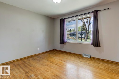 Room featuring wood-finish flooring, a window with white trim, and a ceiling-mounted light fixture - 8511 64 Avenue, Edmonton, AB - Indoor Photo Showing Other Room