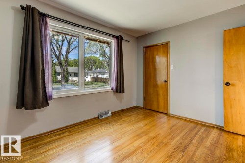 Bright room featuring hardwood flooring, light gray wall paint, and two wood-panel doors - 8511 64 Avenue, Edmonton, AB - Indoor Photo Showing Other Room