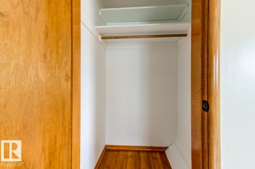 Closet interior featuring a hanging rod, upper shelf, and wood-finish flooring - 8511 64 Avenue, Edmonton, AB - Indoor Photo Showing Other Room