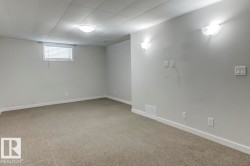 Spacious room with light gray walls, neutral carpet flooring, and a drop ceiling - 