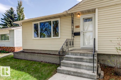 Exterior featuring light-colored horizontal siding, a white front door with a decorative glass insert, and a matching storm door - 8511 64 Avenue, Edmonton, AB - Outdoor With Exterior