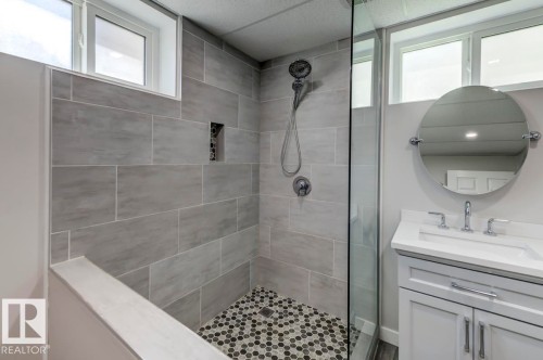 Shower with large format gray wall tile, built-in niche, and mosaic tile flooring - 8511 64 Avenue, Edmonton, AB - Indoor Photo Showing Bathroom