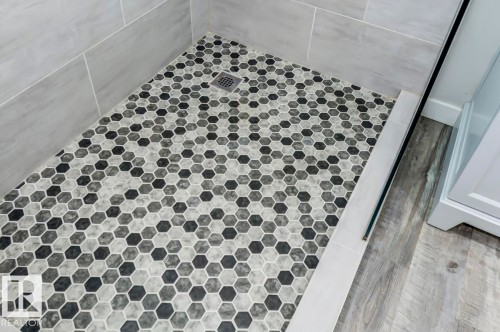 Walk-in shower featuring gray subway tile walls and a hexagonal mosaic tile floor with a central drain - 8511 64 Avenue, Edmonton, AB - Indoor Photo Showing Bathroom