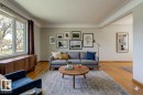 Living area featuring wood-finish flooring, a broad picture window, a built-in wood-finish console, and crown molding - 8511 64 Avenue, Edmonton, AB  - Indoor Photo Showing Living Room 