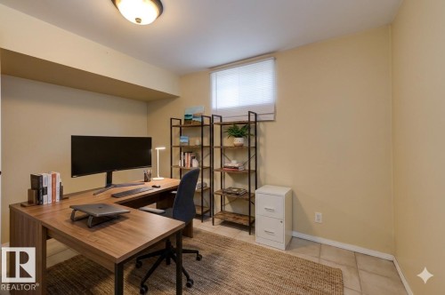 Dedicated workspace featuring a wood-finish L-shaped desk, recessed lighting, and tile flooring - 8511 64 Avenue, Edmonton, AB - Indoor Photo Showing Office